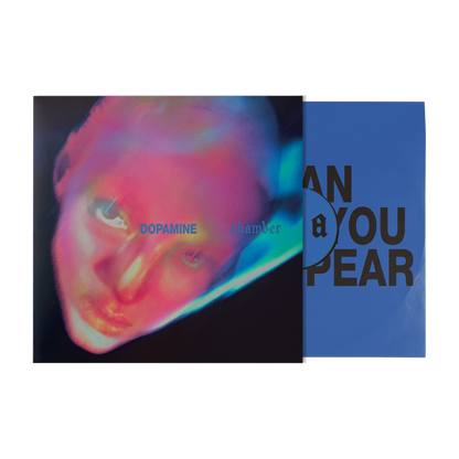 A vinyl record partially pulled from its sleeve, showing the album cover art with a neon close-up portrait and the blue inner sleeve with large black text.