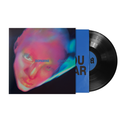 A vinyl record partially pulled from its sleeve, showing a black LP with a blue center label and a colorful album cover.
